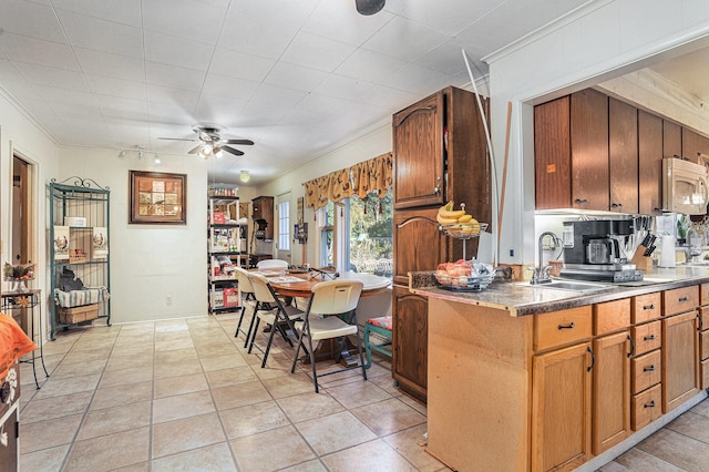 kitchen with ceiling fan, sink, light tile patterned floors, and ornamental molding