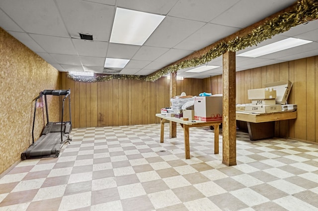 basement with a paneled ceiling and wood walls