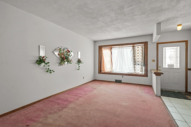 entryway featuring a wealth of natural light, light colored carpet, and a textured ceiling