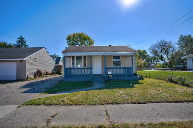 bungalow with a porch, a front lawn, an outdoor structure, and a garage