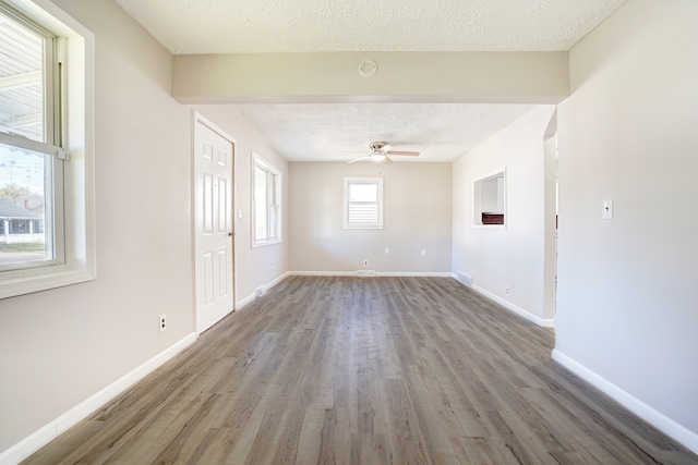 unfurnished room with a ceiling fan, visible vents, wood finished floors, baseboards, and a textured ceiling