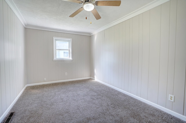 empty room featuring a ceiling fan, baseboards, visible vents, crown molding, and carpet flooring