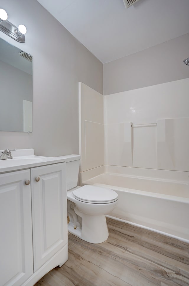 bathroom featuring vanity, wood finished floors, visible vents, shower / tub combination, and toilet