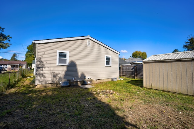 back of property with a yard, an outbuilding, a fenced backyard, and a storage shed