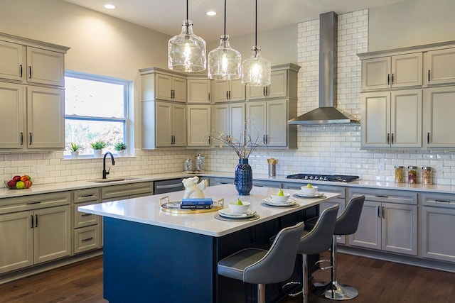 kitchen with wall chimney exhaust hood, a kitchen island, sink, and tasteful backsplash