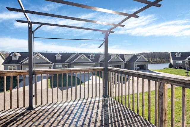 wooden deck featuring a pergola, a lawn, and a water view