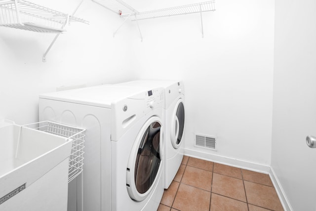 clothes washing area with separate washer and dryer, sink, and light tile patterned floors