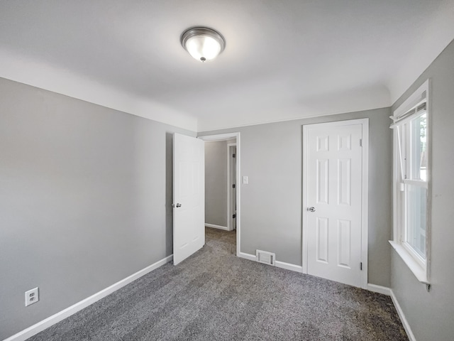 unfurnished bedroom featuring dark carpet and a closet