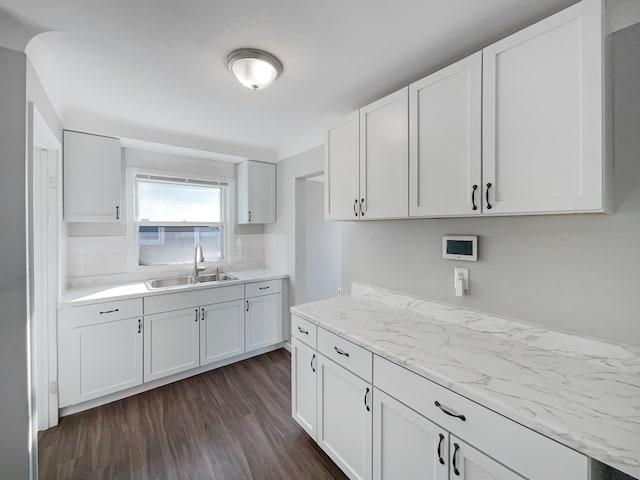 kitchen featuring light stone countertops, dark hardwood / wood-style flooring, white cabinetry, and sink