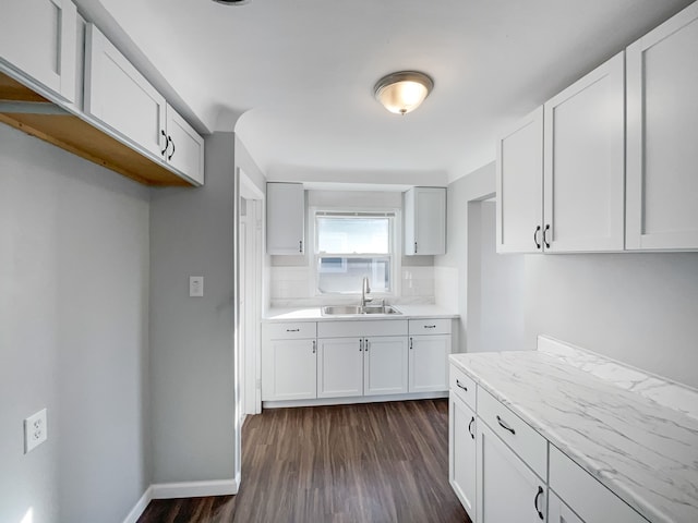 kitchen featuring dark hardwood / wood-style flooring, white cabinetry, sink, and light stone counters