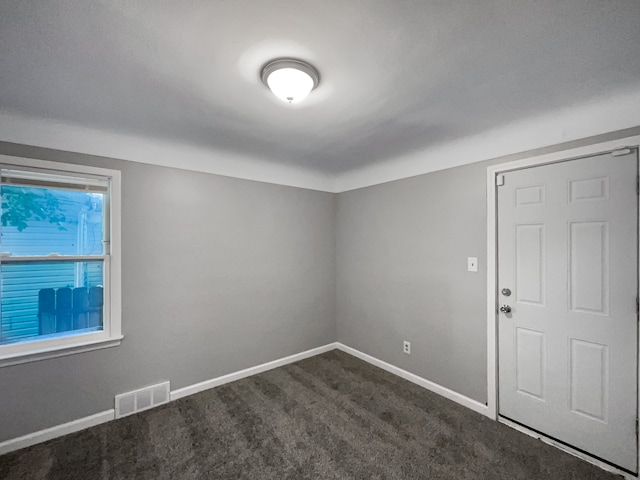 unfurnished room with dark colored carpet