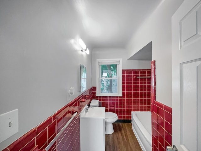 bathroom with vanity, a bathing tub, toilet, tile walls, and wood-type flooring