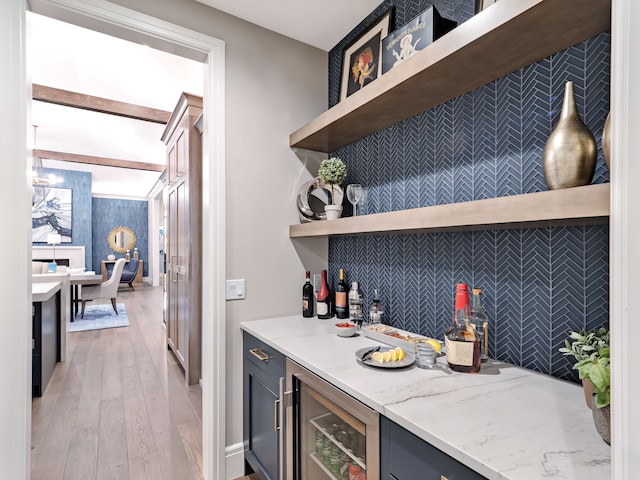 bar featuring light stone countertops, light wood-type flooring, and wine cooler