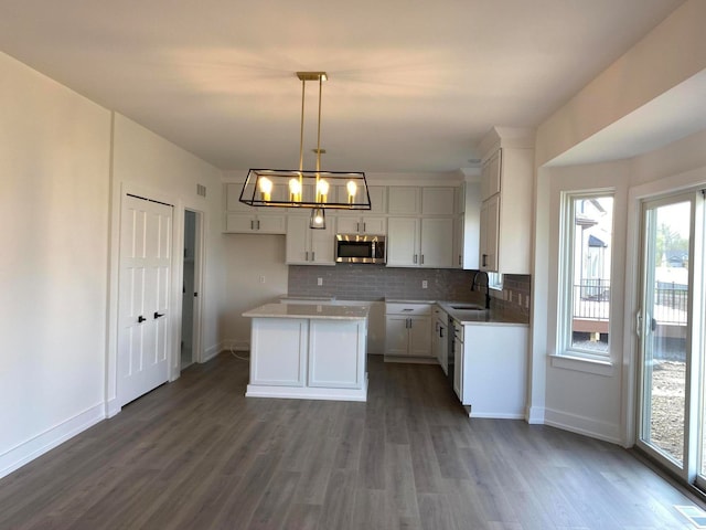 kitchen with a center island, dark wood-type flooring, sink, hanging light fixtures, and white cabinetry