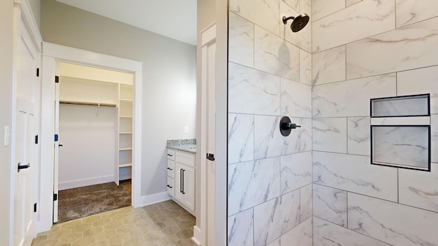 bathroom with a tile shower and vanity