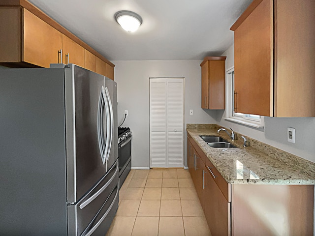 kitchen featuring light stone counters, sink, light tile patterned floors, and stainless steel appliances