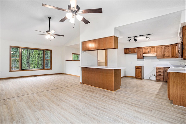 kitchen featuring light hardwood / wood-style floors, kitchen peninsula, ceiling fan, sink, and lofted ceiling