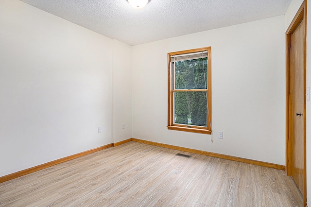 empty room with a textured ceiling and light hardwood / wood-style floors