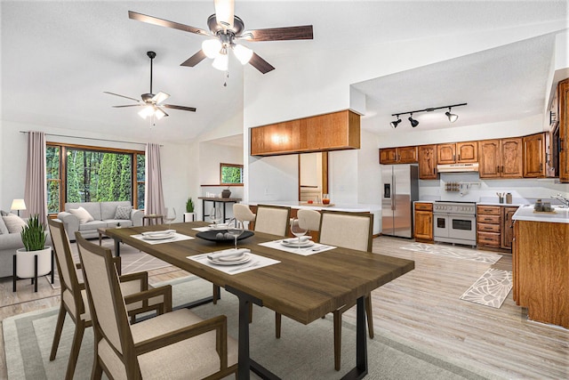 dining space with sink, a textured ceiling, ceiling fan, light hardwood / wood-style floors, and high vaulted ceiling