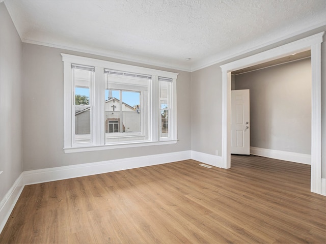 unfurnished room with light hardwood / wood-style flooring, a textured ceiling, and ornamental molding