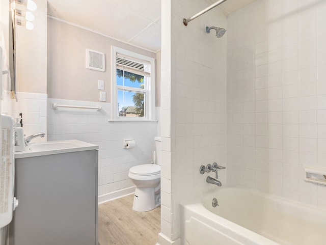 full bathroom featuring hardwood / wood-style floors, toilet, vanity, tile walls, and tiled shower / bath