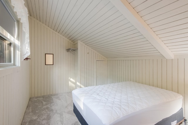 carpeted bedroom featuring lofted ceiling with beams, wooden walls, and wood ceiling