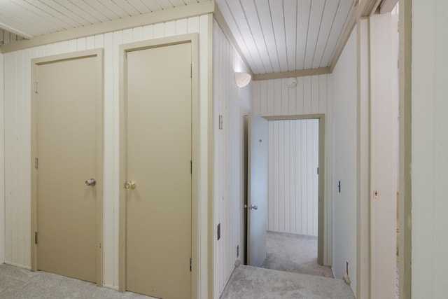 corridor featuring light carpet, wood ceiling, and wood walls