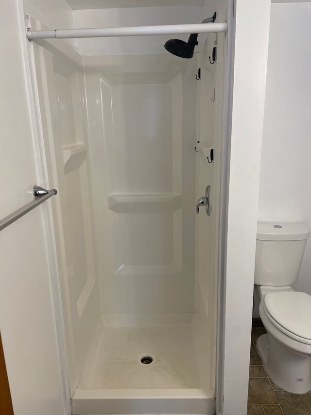 bathroom featuring tile patterned flooring, toilet, and walk in shower