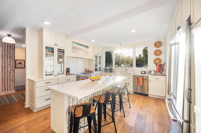 kitchen with a kitchen breakfast bar, white cabinetry, light hardwood / wood-style flooring, and high quality appliances