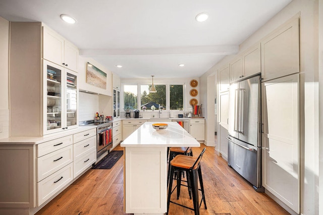 kitchen with beam ceiling, white cabinetry, stainless steel appliances, a kitchen bar, and a kitchen island