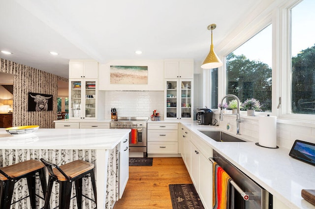 kitchen featuring sink, backsplash, pendant lighting, a kitchen bar, and appliances with stainless steel finishes