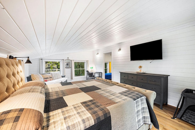 bedroom with wood walls, light hardwood / wood-style floors, vaulted ceiling, and wooden ceiling