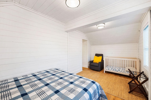 bedroom featuring wood walls, light hardwood / wood-style flooring, and vaulted ceiling