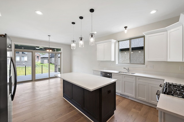 kitchen with light hardwood / wood-style floors, decorative light fixtures, a kitchen island, white cabinetry, and stainless steel appliances