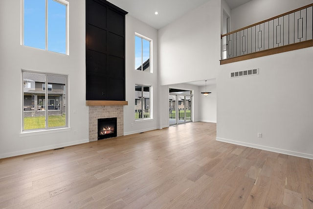 unfurnished living room with a fireplace, a towering ceiling, and a wealth of natural light