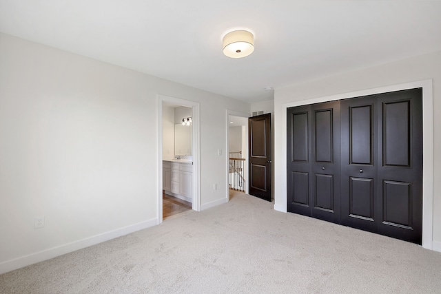 unfurnished bedroom with ensuite bathroom, carpet floors, sink, and a closet