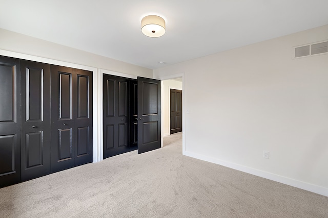 unfurnished bedroom with light carpet and multiple closets