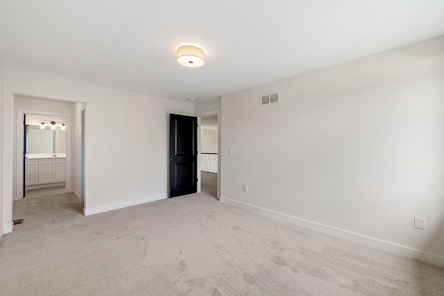 unfurnished bedroom featuring light colored carpet and ensuite bath