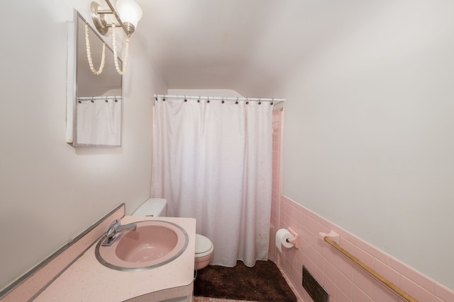 bathroom featuring toilet, sink, and tile walls