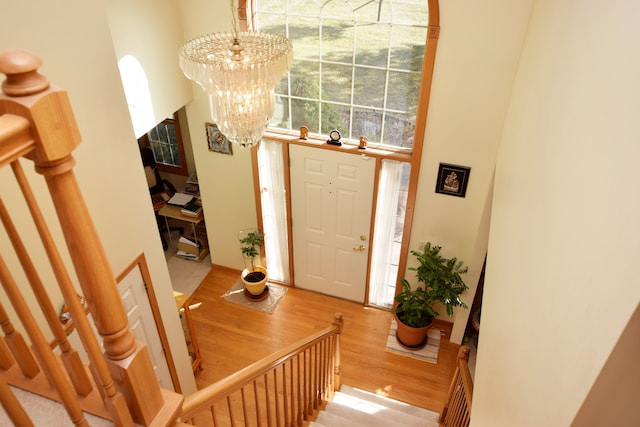 entrance foyer with an inviting chandelier, a towering ceiling, and light wood-type flooring