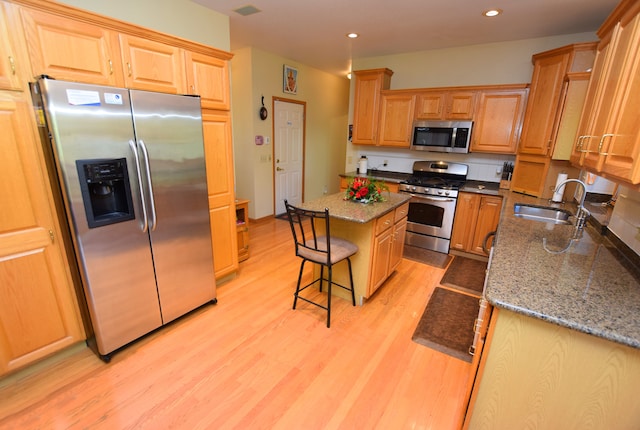 kitchen with light wood-type flooring, a center island, stainless steel appliances, and sink