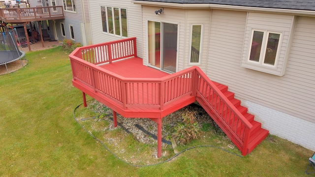 wooden deck with a trampoline and a yard