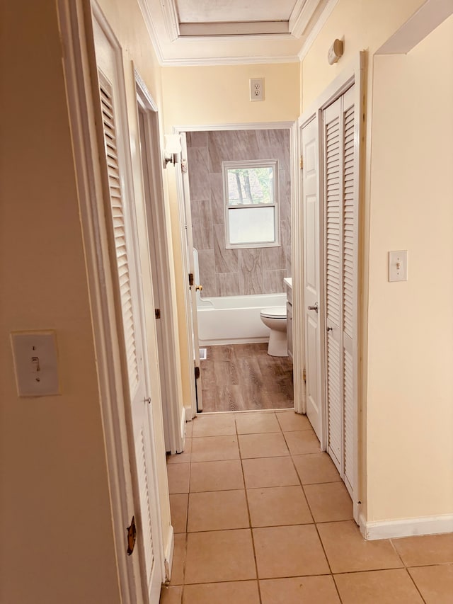 corridor featuring light tile patterned floors and crown molding