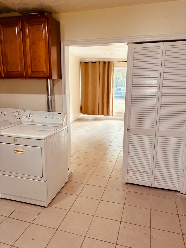 laundry area featuring cabinets, washer and clothes dryer, and light tile patterned flooring