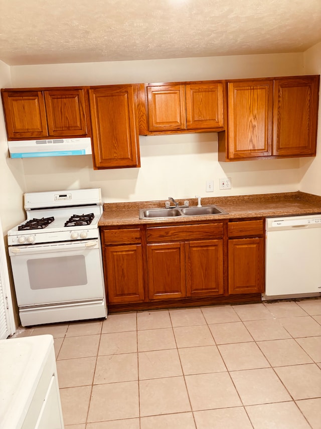 kitchen with a textured ceiling, sink, light tile patterned floors, and white appliances