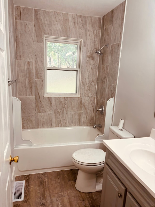 full bathroom with hardwood / wood-style floors, vanity, tiled shower / bath combo, and toilet