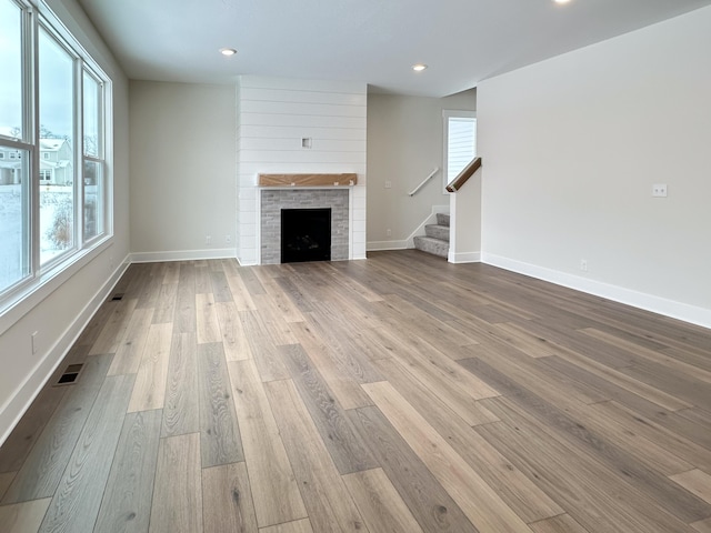 unfurnished living room featuring plenty of natural light, a fireplace, and light hardwood / wood-style floors