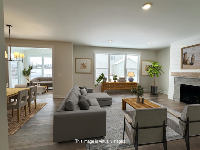 living room with a tiled fireplace, wood-type flooring, and a healthy amount of sunlight