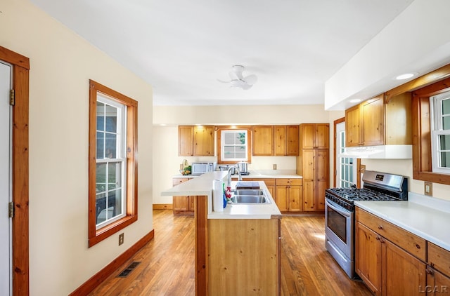 kitchen with a center island with sink, sink, light hardwood / wood-style flooring, and stainless steel range with gas stovetop