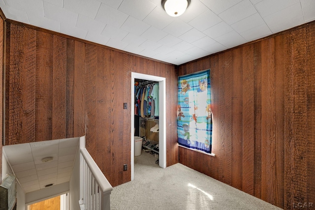 hall featuring carpet flooring and wooden walls